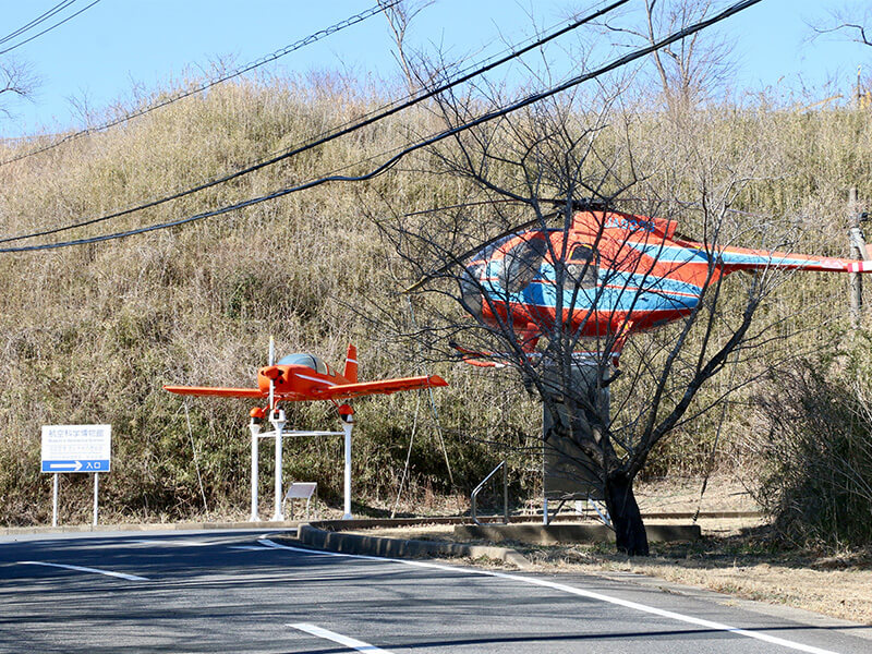 オレンジ色の軽飛行機とヘリコプターのある博物館の敷地入口